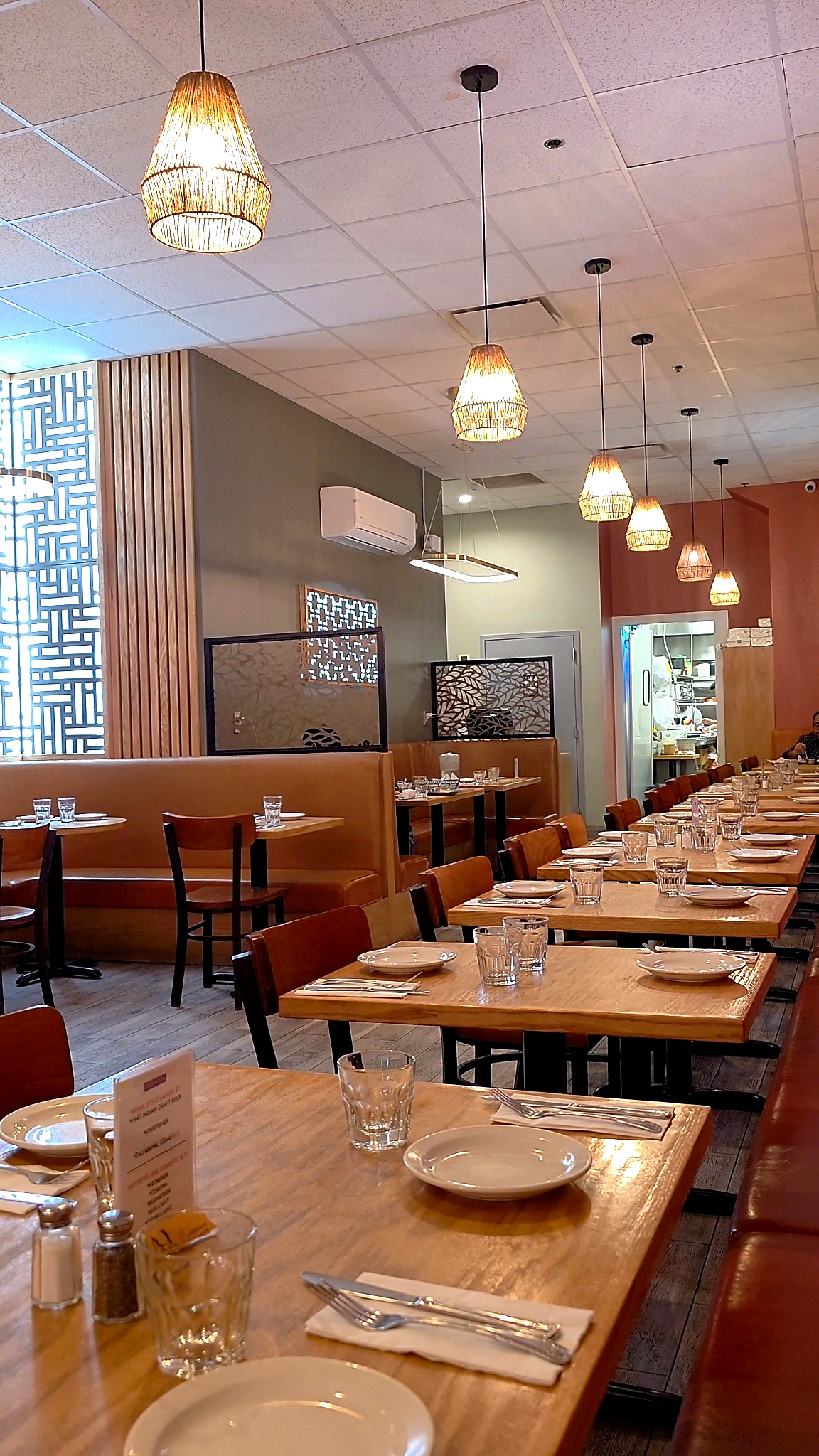 Modern and clean interior dining room of Jackson Diner with warm wooden tables, booth seating, and elegant hanging wicker basket lights.