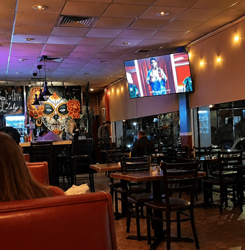 The indoor dining room and bar seating area at Laly's Restaurant featuring a colorful Dia de los Muertos skull mural