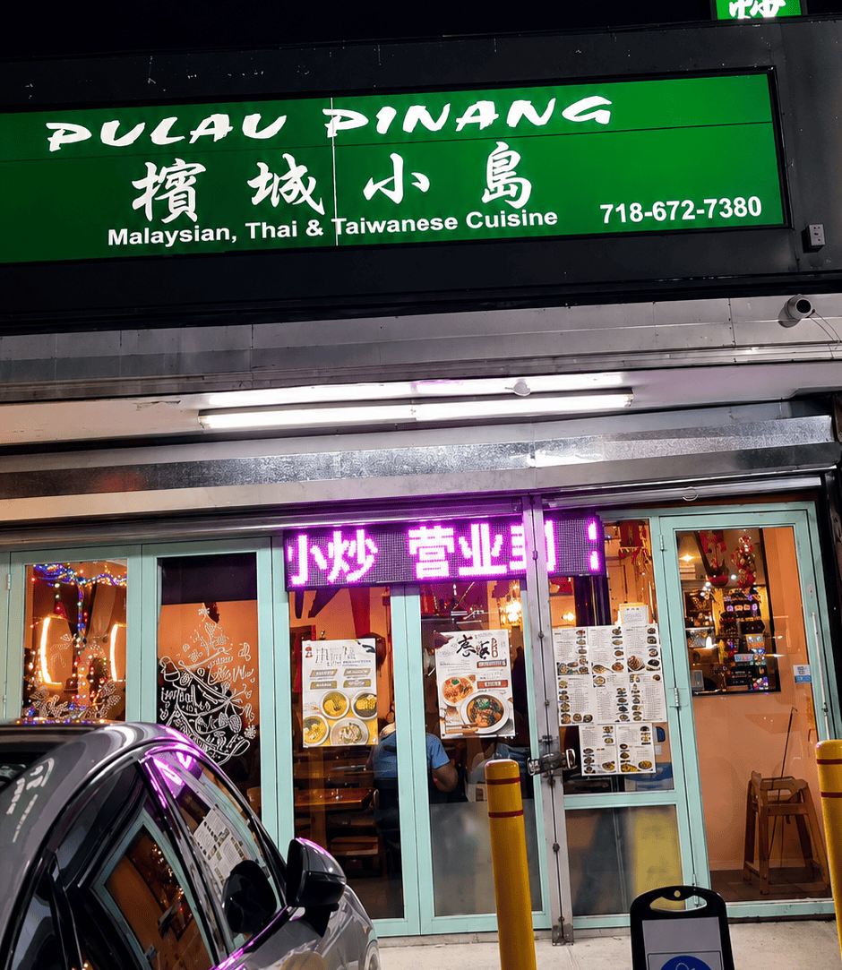 Green storefront sign for Pulau Pinang restaurant in Elmhurst Queens reading Malaysian Thai and Taiwanese Cuisine.
