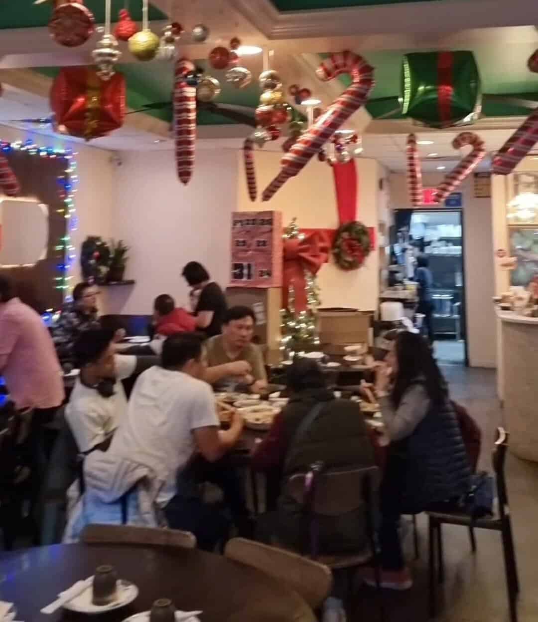 Busy dining room at Pulau Pinang restaurant packed with families and decorated with festive holiday ornaments.