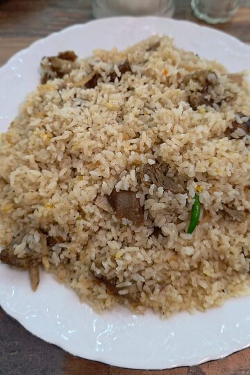 A generous plate of aromatic basmati goat biryani loaded with tender chunks of seasoned goat meat and fresh green chilies.