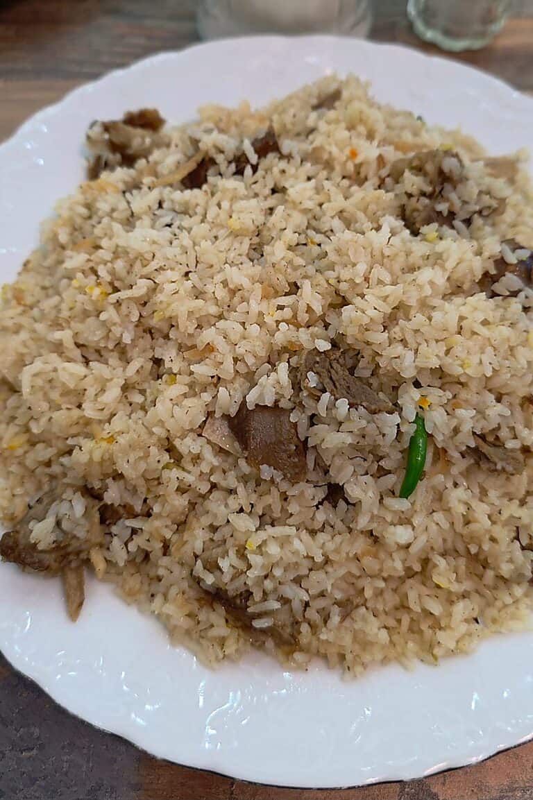 A generous plate of aromatic basmati goat biryani loaded with tender chunks of seasoned goat meat and fresh green chilies.