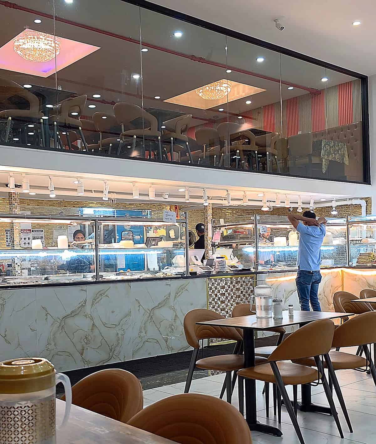 The bright, modern, and spacious interior dining area of Shanai Restaurant with a view of a mezzanine level and food counter.