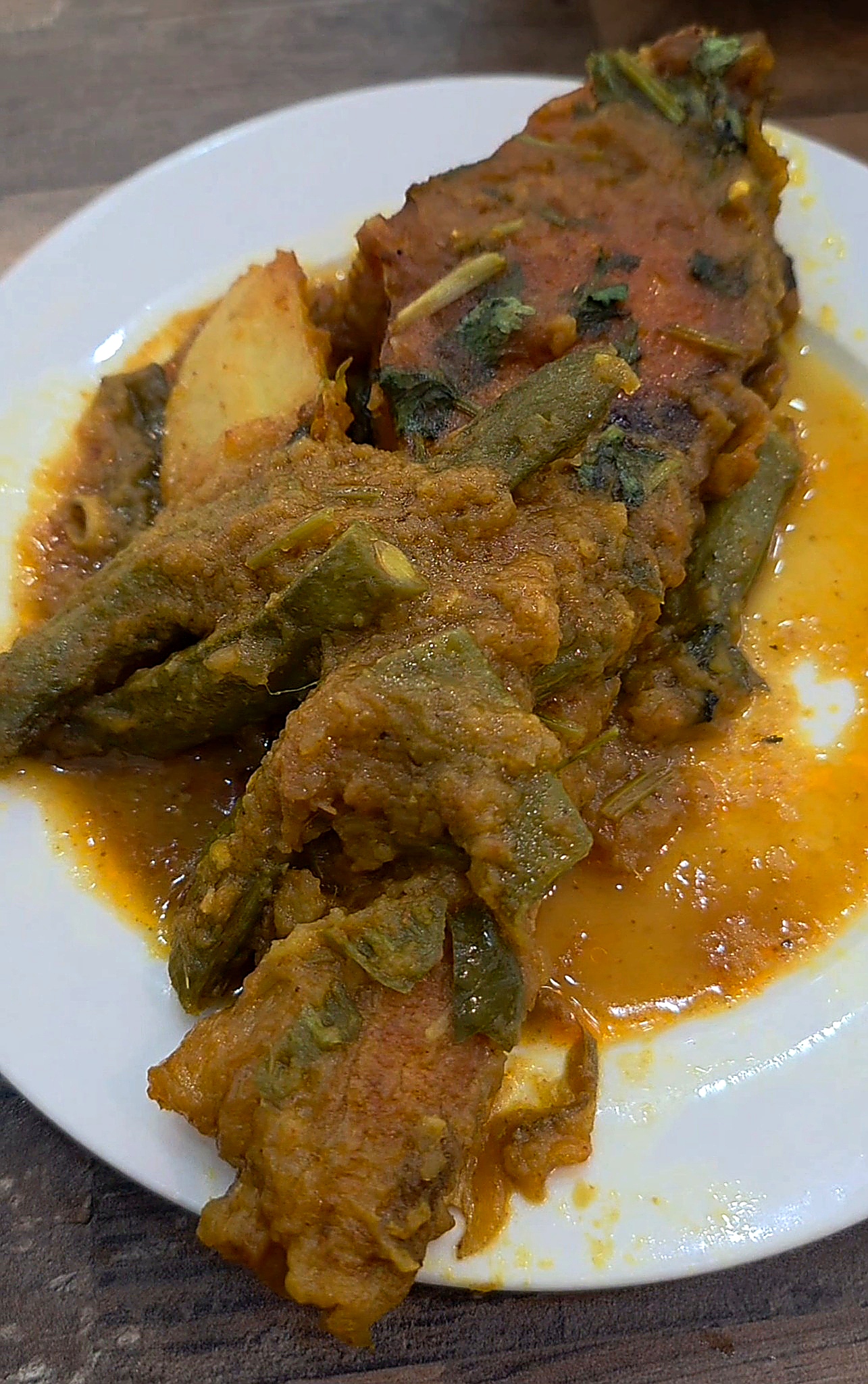South Asian style fish curry steak served with green chilies, herbs, and potatoes in an aromatic orange-brown sauce.