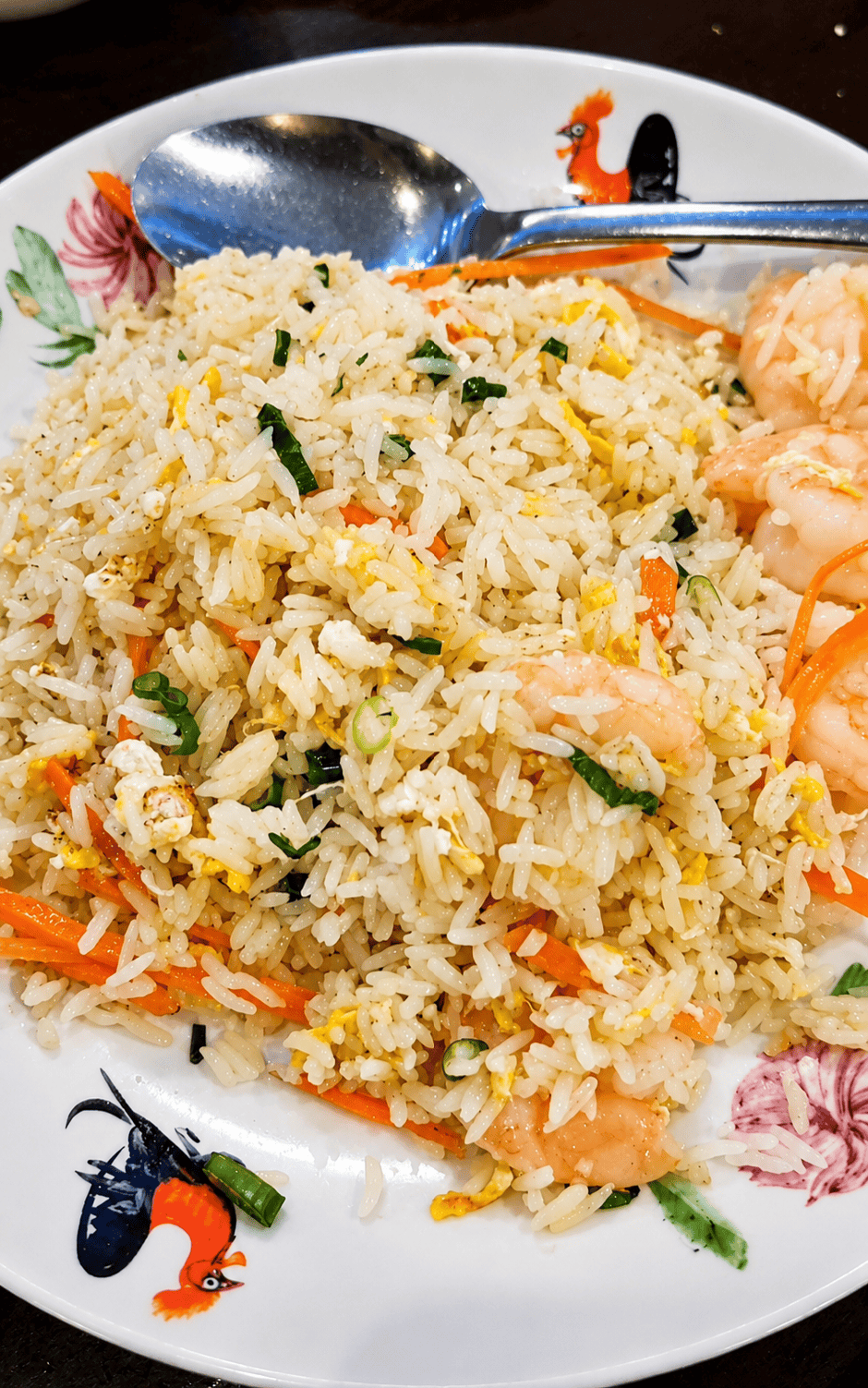 A generous portion of shrimp fried rice served on a traditional ceramic plate with a rooster design.