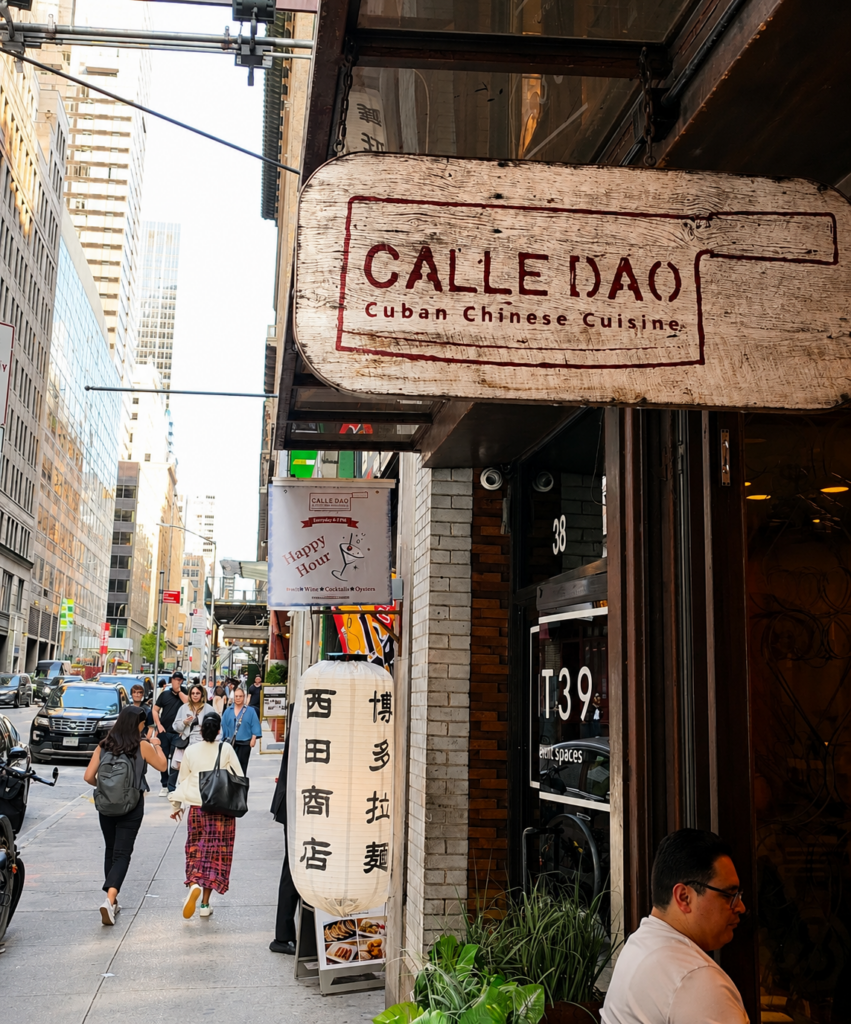 The rustic wooden exterior sign of Calle Dao Cuban Chinese Cuisine on a busy Midtown Manhattan sidewalk.