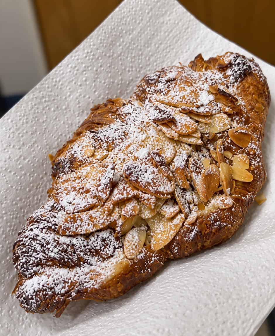 Almond chocolate croissant topped with sliced almonds and powdered sugar at L'Appartement 4F