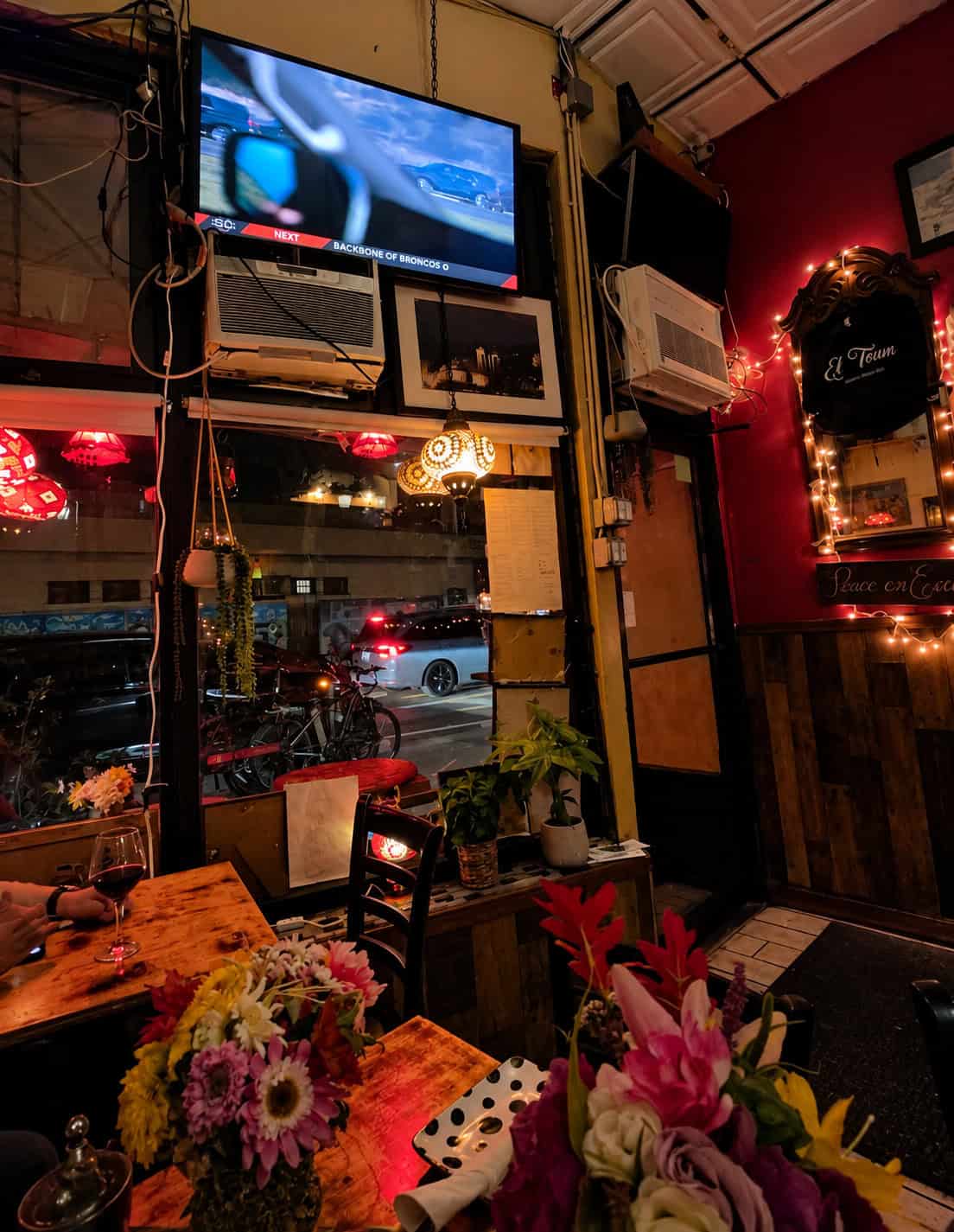 Table setting near the front window at El Toum with fresh flowers and warm hanging lamps