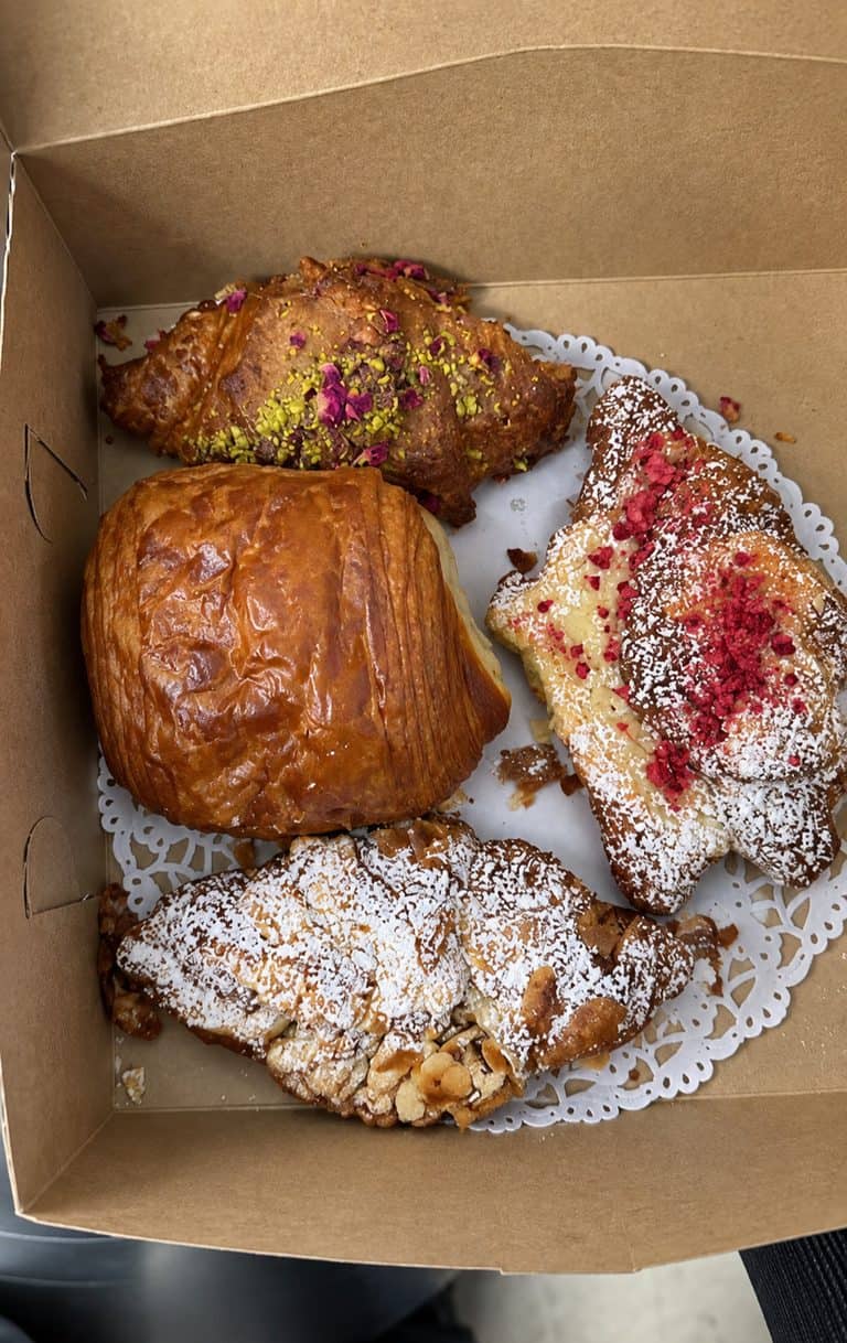 Box of pistachio, almond chocolate, raspberry, and pain au chocolat pastries from L'Appartement 4F