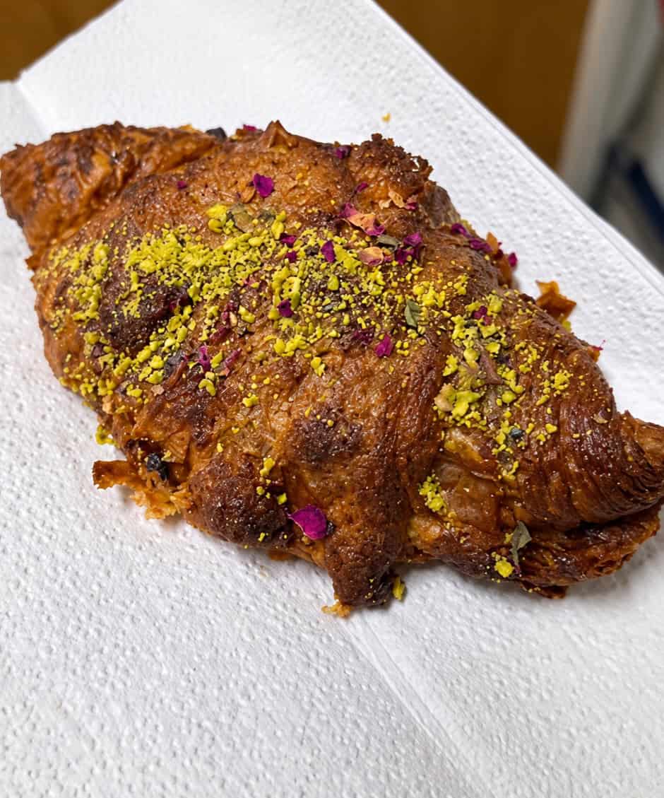 Pistachio croissant topped with crushed pistachios and rose petals at L'Appartement 4F
