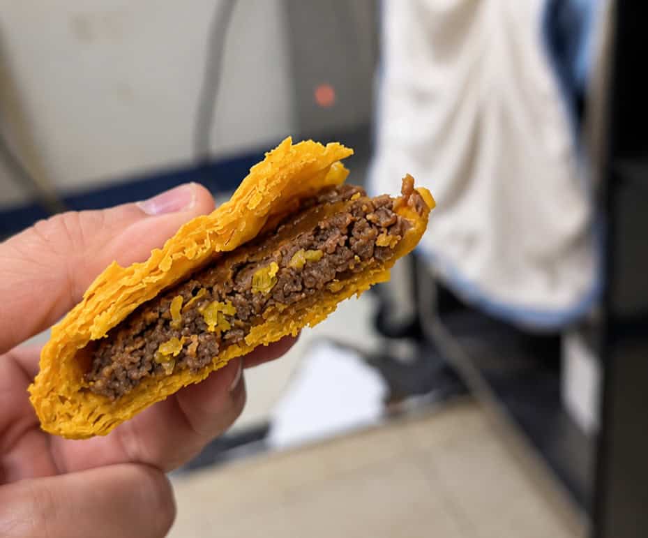 Cross-section shot of a Jamaican beef patty showing seasoned ground beef filling and flaky turmeric pastry crust