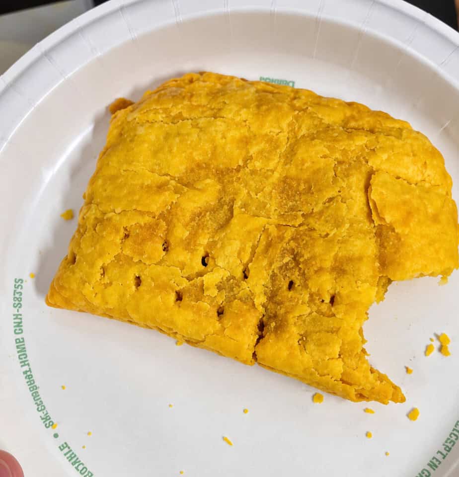 Top view of a golden flaky Jamaican beef patty with a bite taken out at Robinson Valley in Brooklyn