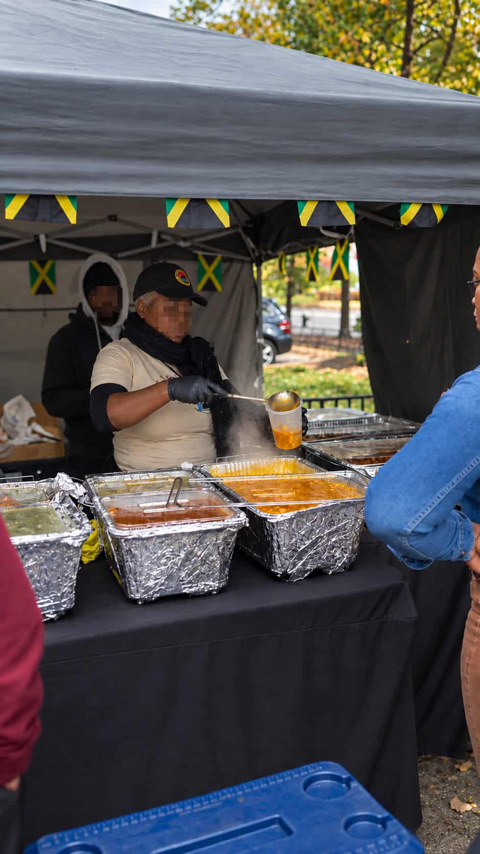 Friendly staff serving hot Jamaican food under the Robinson Valley outdoor tent setup in Downtown Brooklyn