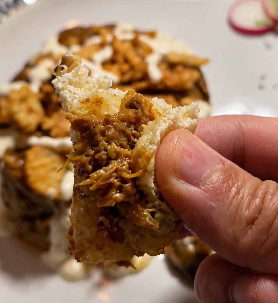 Close up of a piece of pita bread scooping up rich Kashke Bademjoon eggplant dip