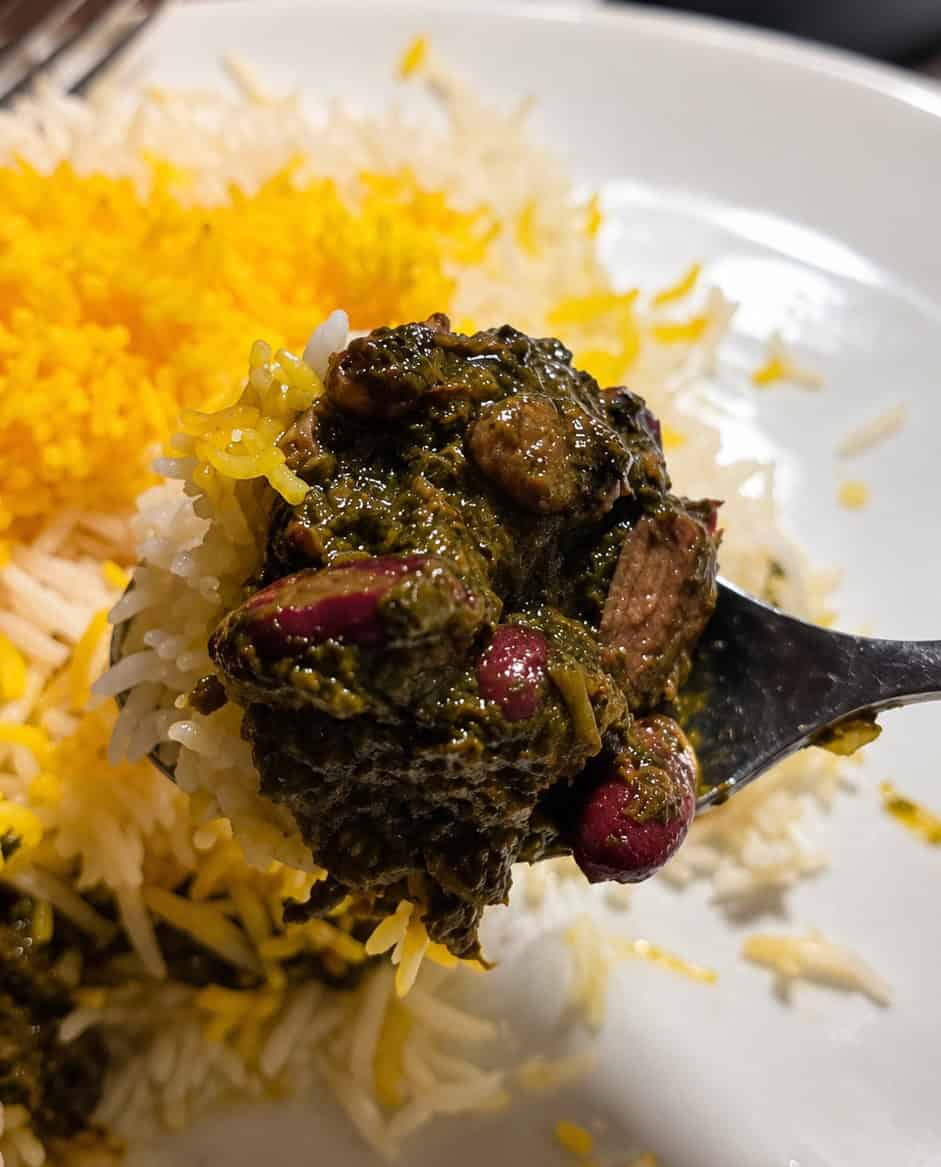 Spoonful of Ghormeh Sabzi herb stew and tender beef over basmati rice