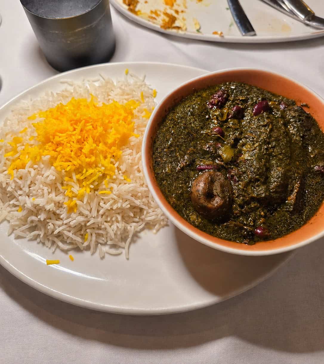 Bowl of dark green Ghormeh Sabzi herb stew served alongside white basmati rice