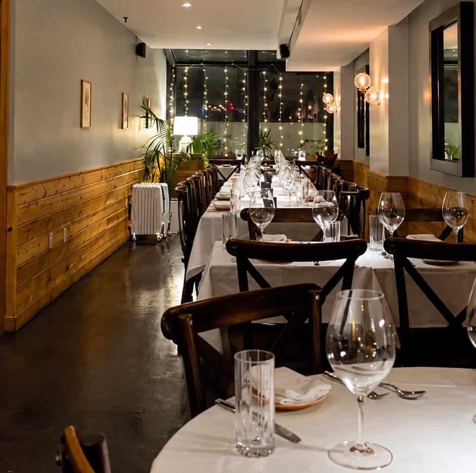 Long hallway dining room setup with white tablecloths and warm lighting at Shiraz Kitchen