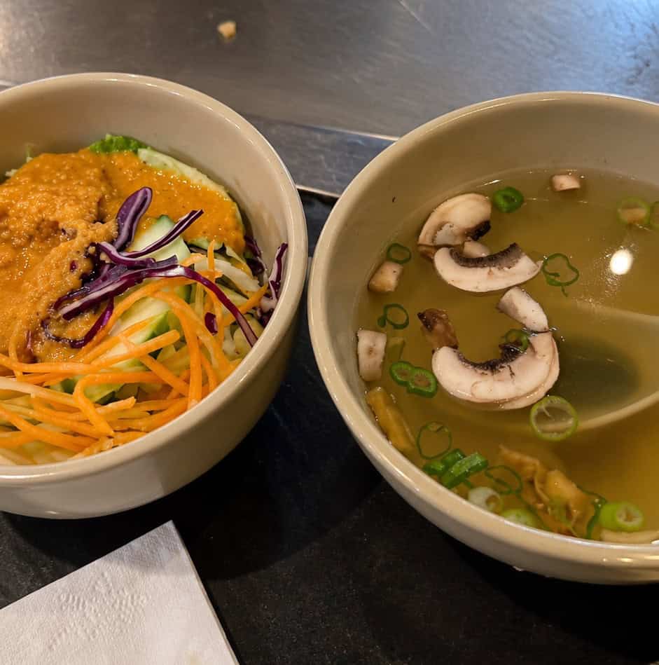 White ceramic bowls containing Japanese clear mushroom soup and garden salad topped with ginger dressing
