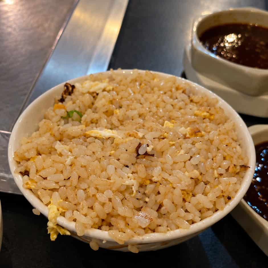 Overflowing bowl of freshly prepared hibachi egg fried rice cooked on the teppanyaki flat top