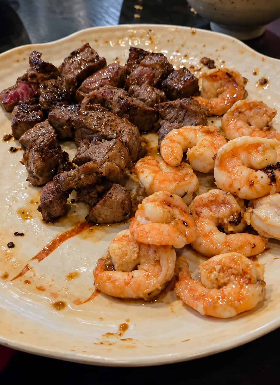 Plate filled with seared steak cubes and grilled shrimp served with hibachi dipping sauces