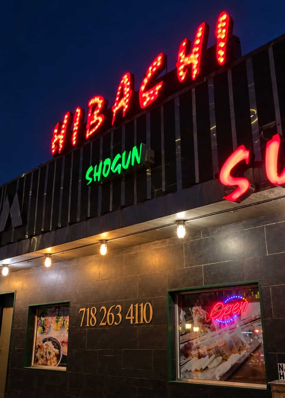 Exterior illuminated red and green neon signage for Shogun Hibachi and Sushi on Queens Boulevard in Forest Hills Queens