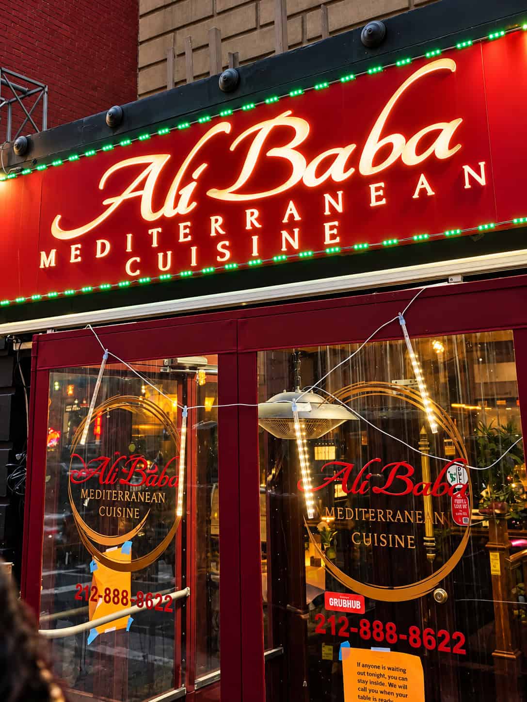 Red lit storefront and entrance of Ali Baba Mediterranean Cuisine on East 53rd Street in Midtown Manhattan