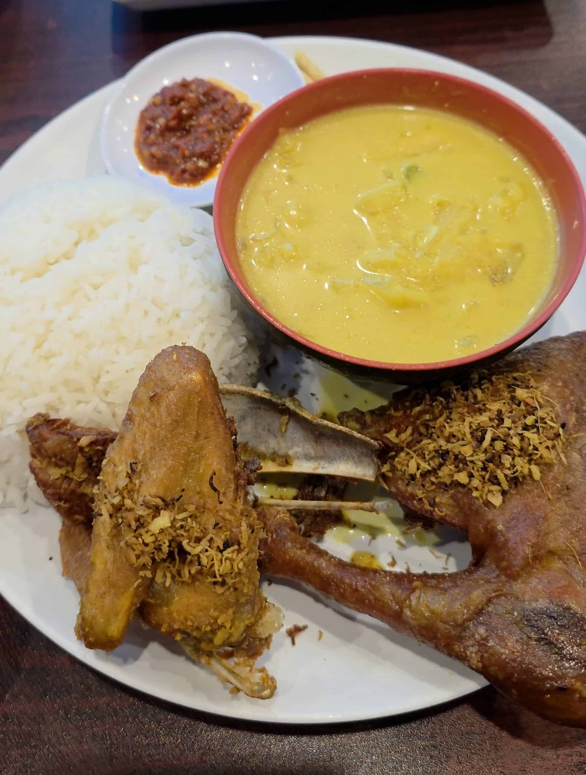 Ayam Goreng Kremes platter featuring crispy fried chicken topped with savory crumbs, steamed rice, vegetable soup, and red sambal