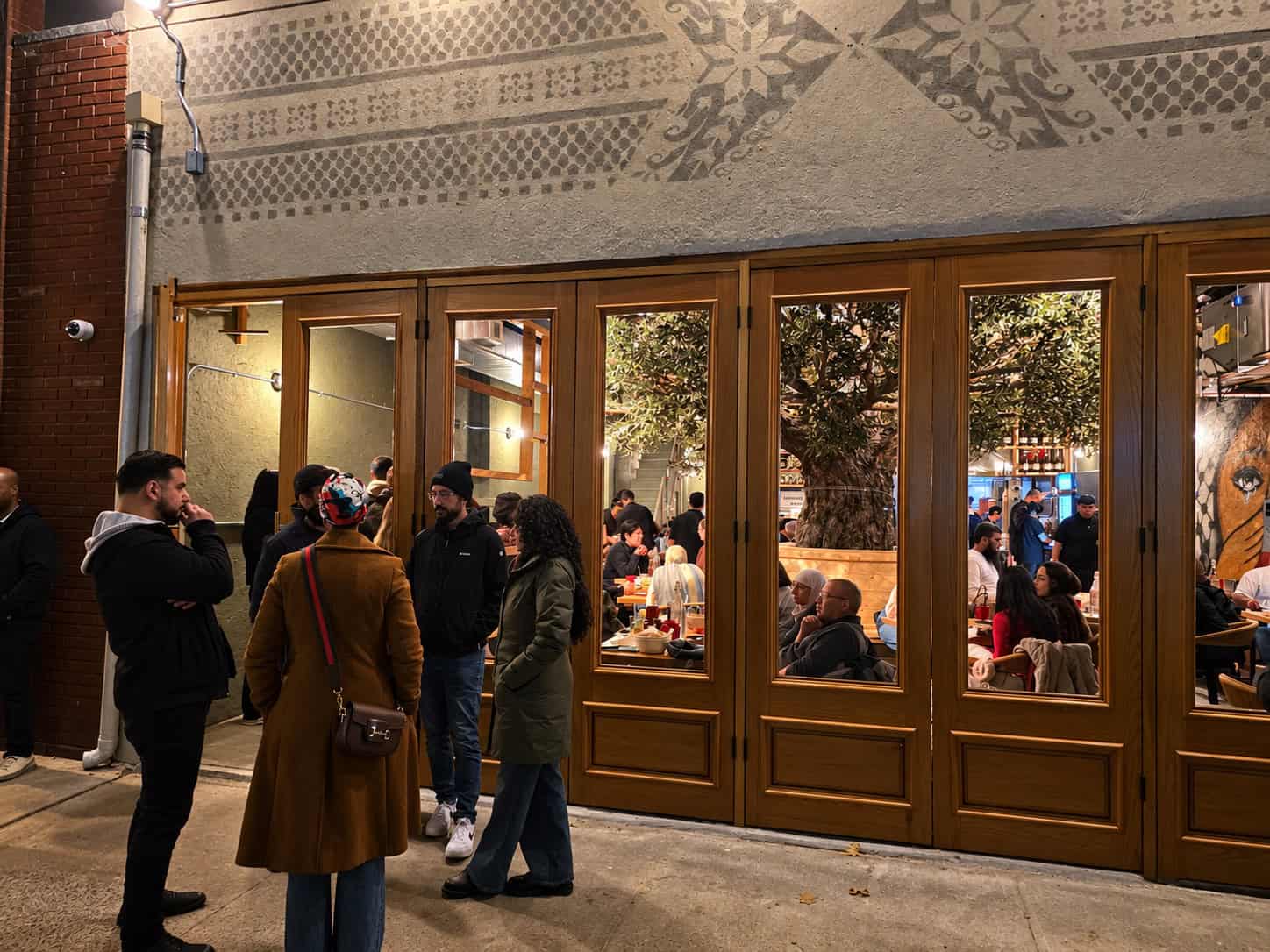 Exterior of Ayat Palestinian Restaurant on Crescent Street in Astoria Queens with crowds waiting outside