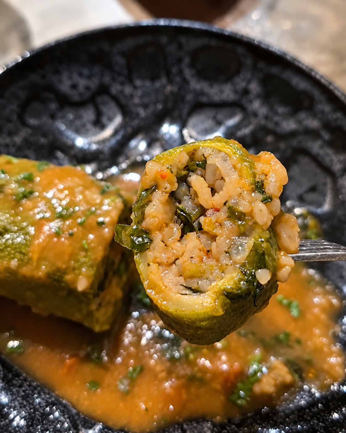 Close-up cross section of stuffed squash showing rice parsley and tomato filling on a fork