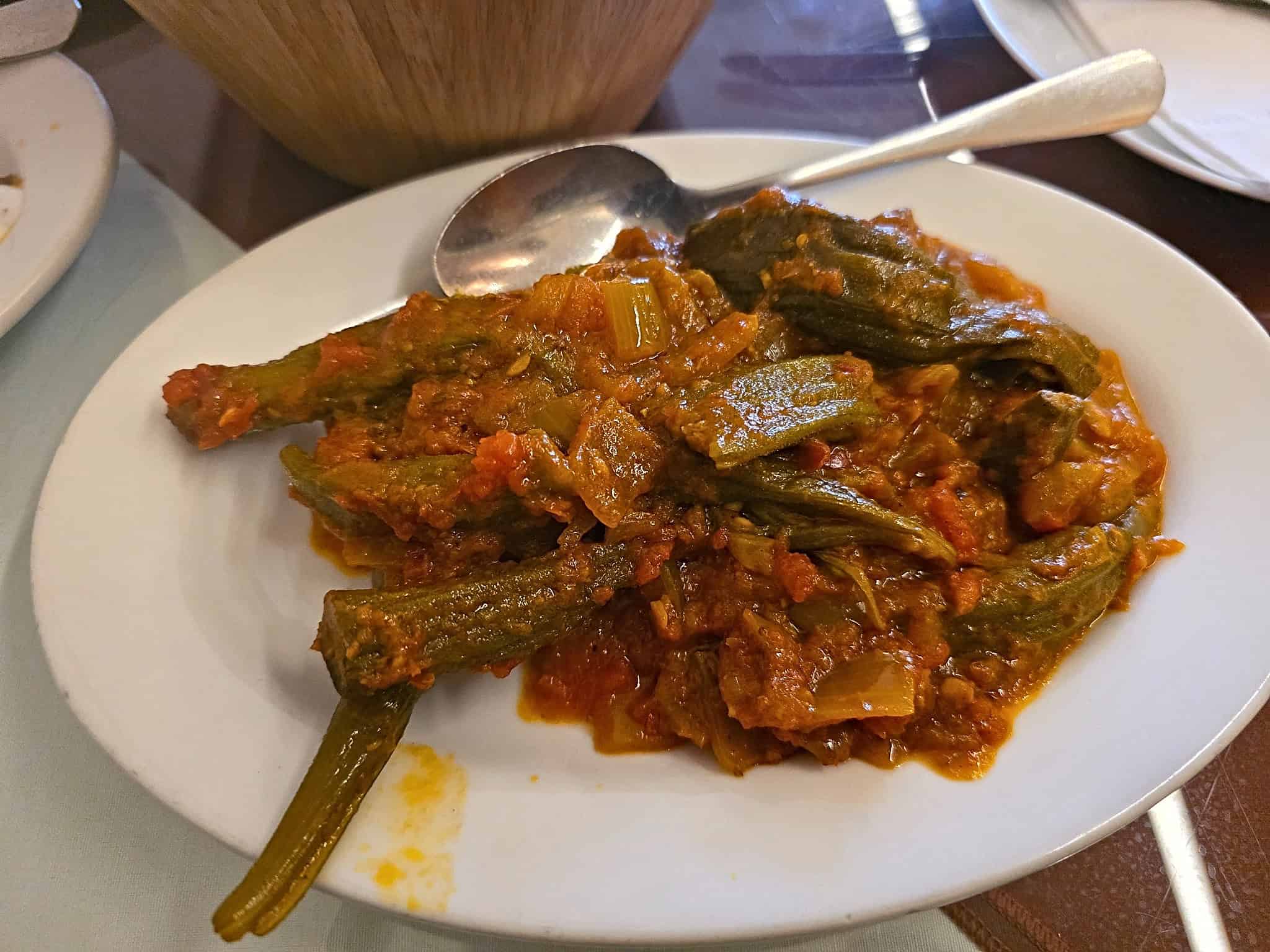 White plate of Afghan Bamia featuring tender okra simmered in a seasoned tomato and onion sauce