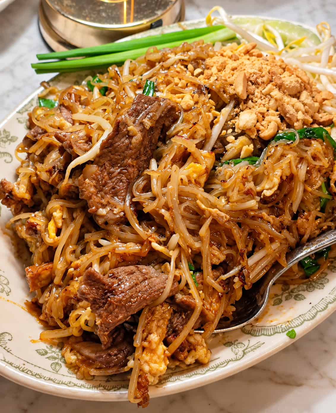 Plate of Beef Pad Thai noodles with tender beef slices crushed peanuts and bean sprouts