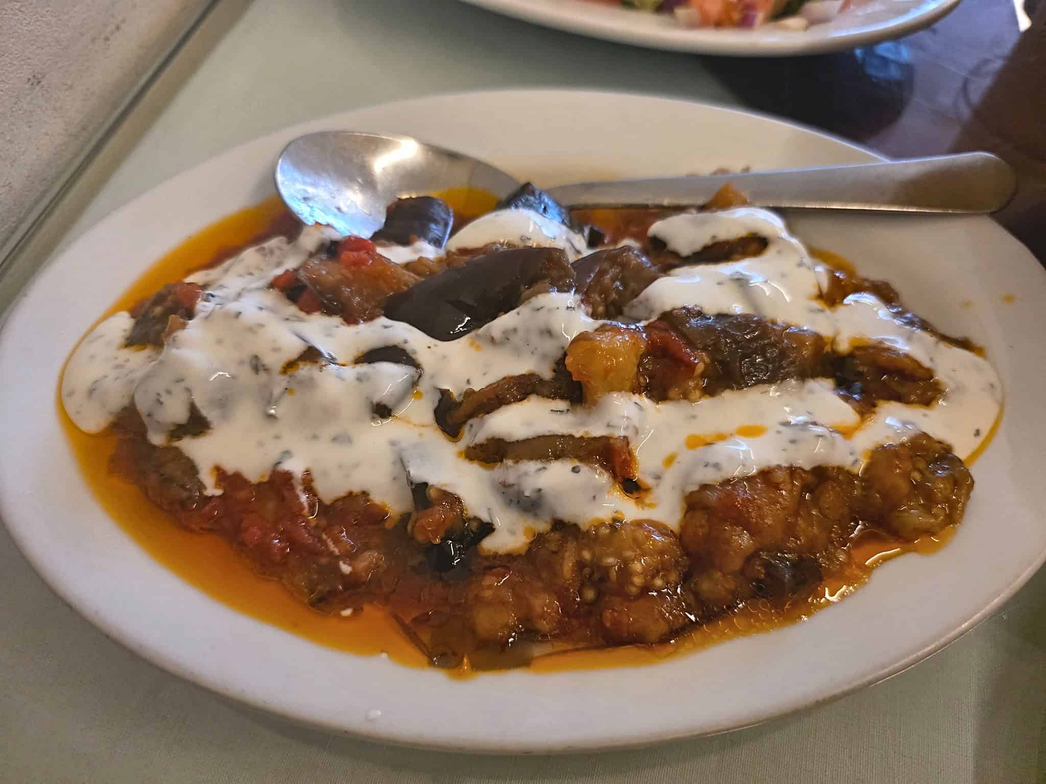 Plate of Borani Banjan roasted Afghan eggplant topped with tomato sauce and creamy garlic yogurt