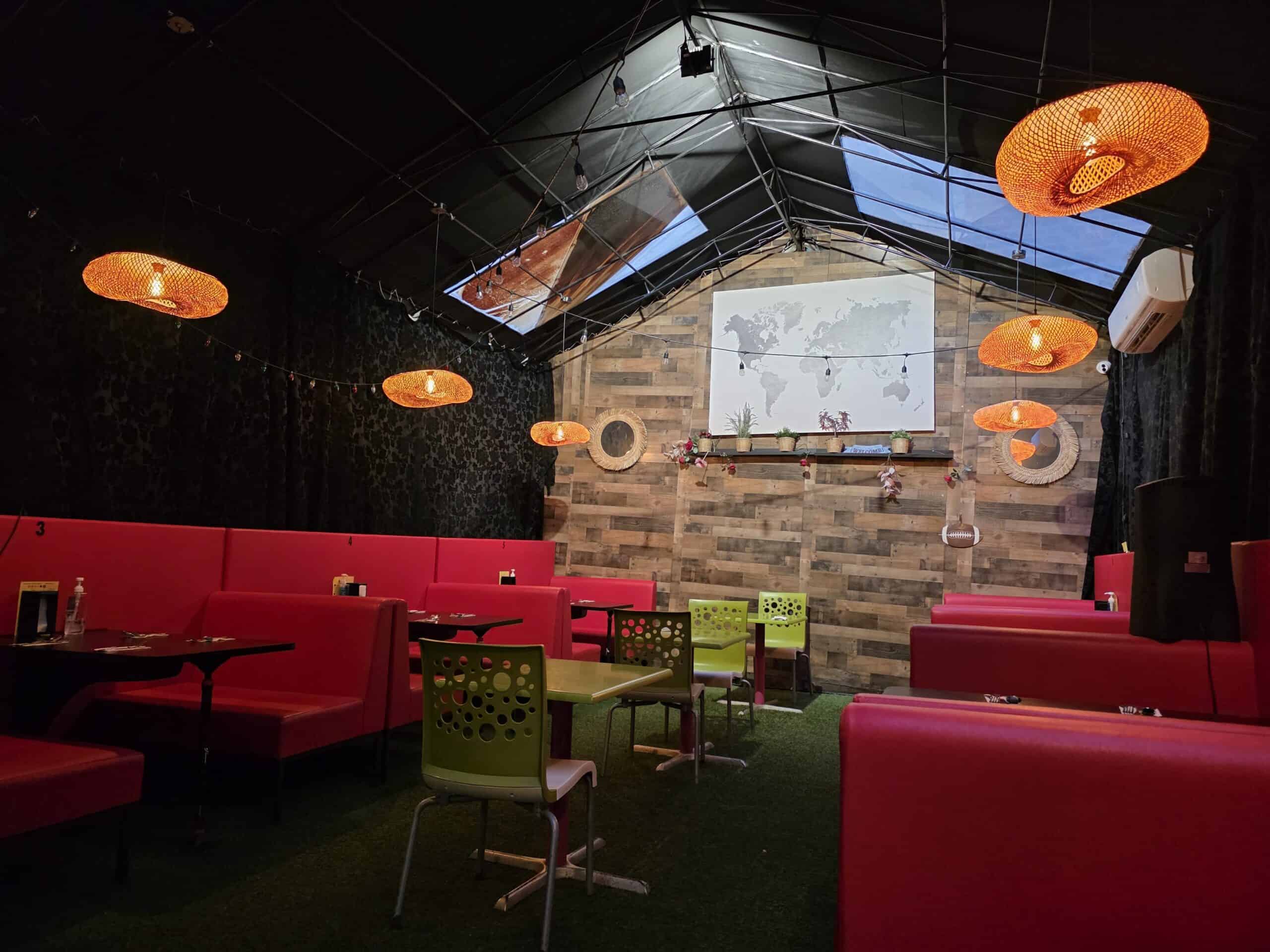 Cozy interior dining section at Cairo Feteer featuring red booth seating, warm basket light fixtures, and a wood accent wall