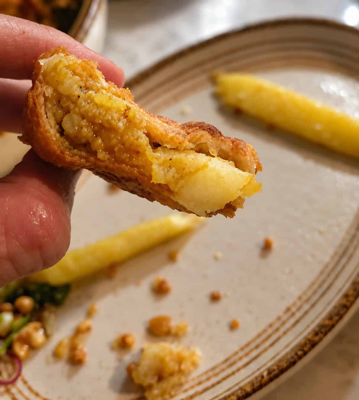 Close up view showing the flaky pastry crust and warm spiced potato filling inside a curry puff