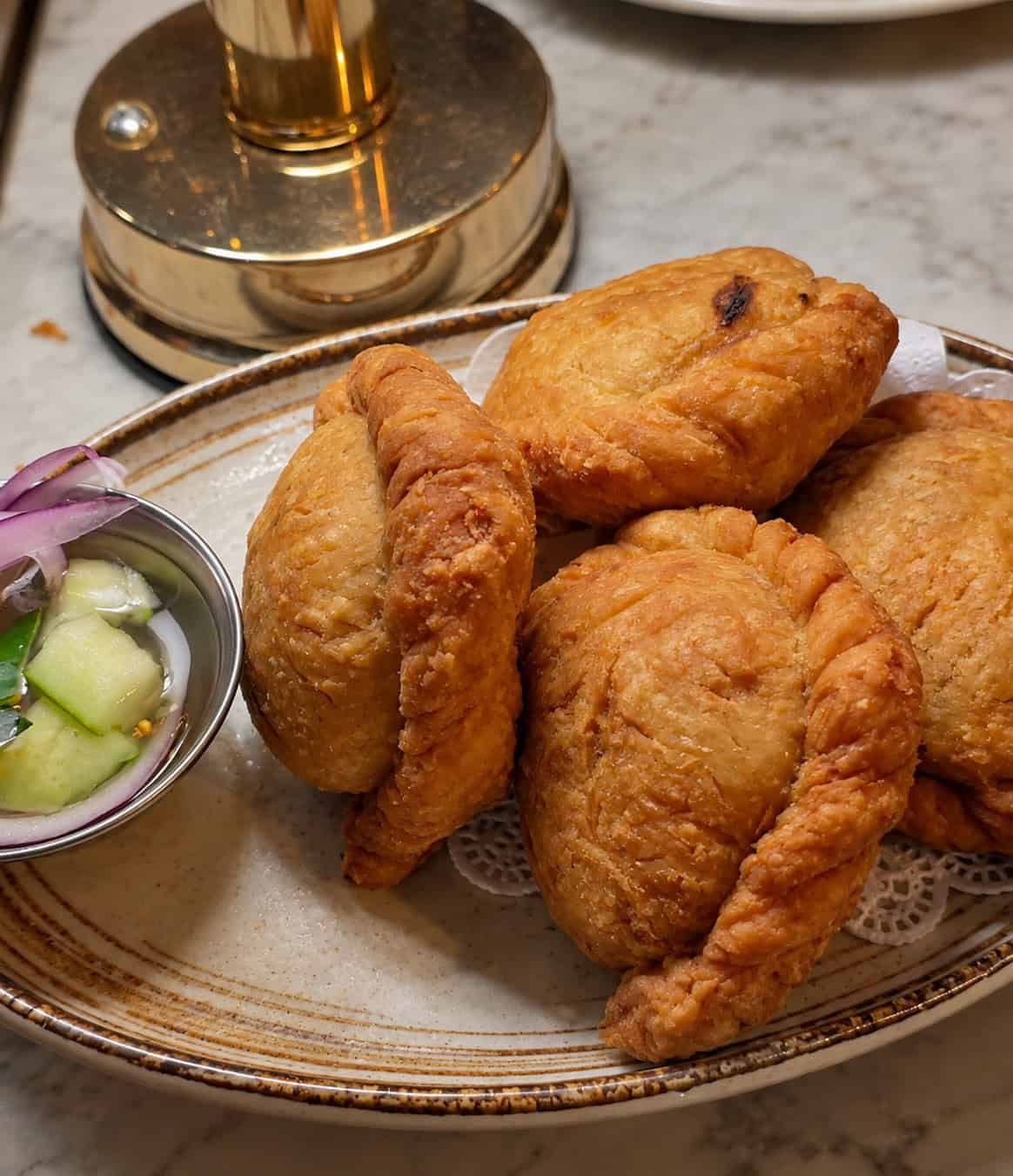Golden flaky fried curry puffs served with a cucumber relish dipping sauce at SaRanRom Thai