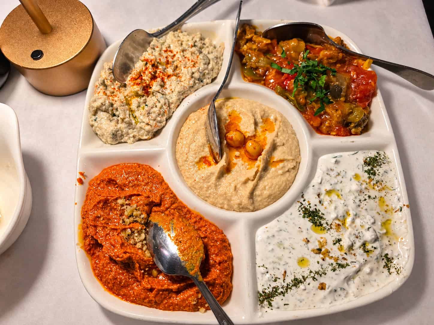 Large divided platter featuring five Turkish dips including hummus, haydari, muhammara, baba ghanoush, and stuffed eggplant