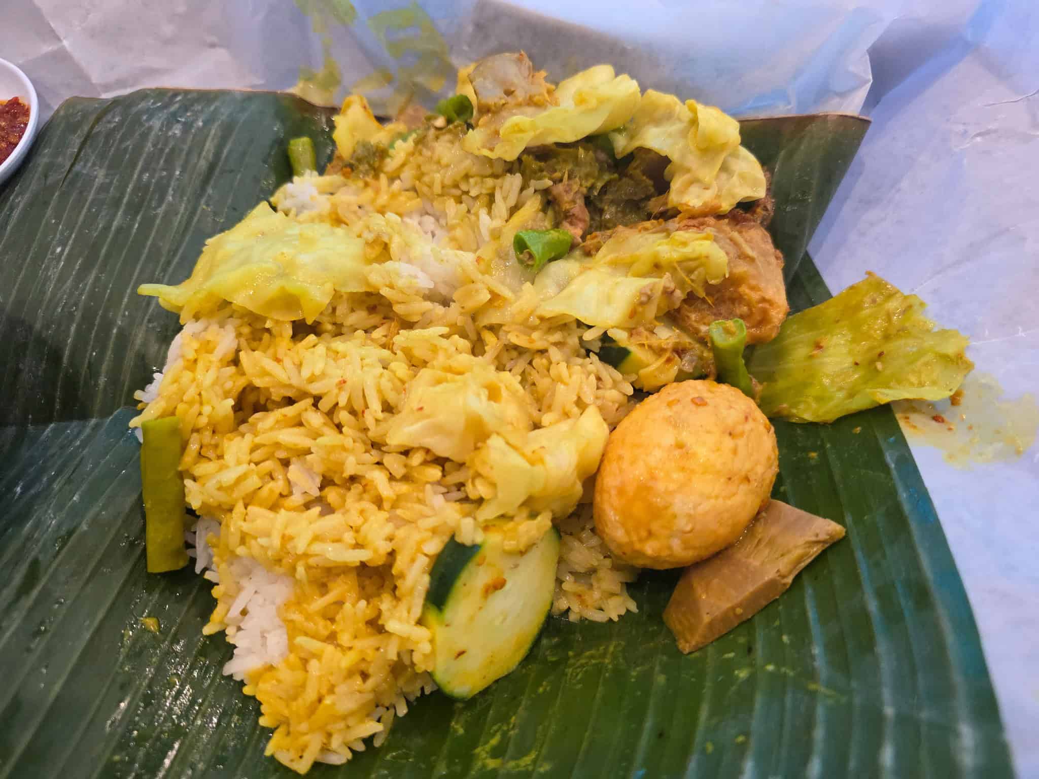 Nasi Bungkus Padang unwrapped on a banana leaf featuring rice, boiled egg, vegetables, and curried jackfruit