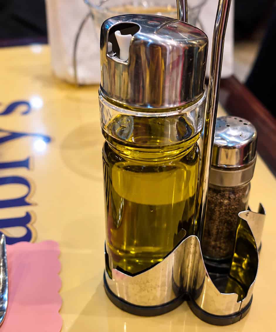 Cruet set containing olive oil and pepper shaker on restaurant table