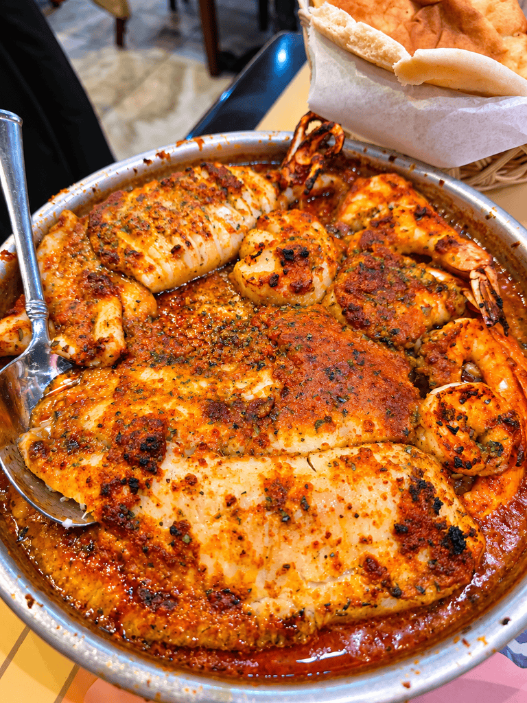 Large metal platter filled with seasoned fish fillets jumbo shrimp scallops and squid