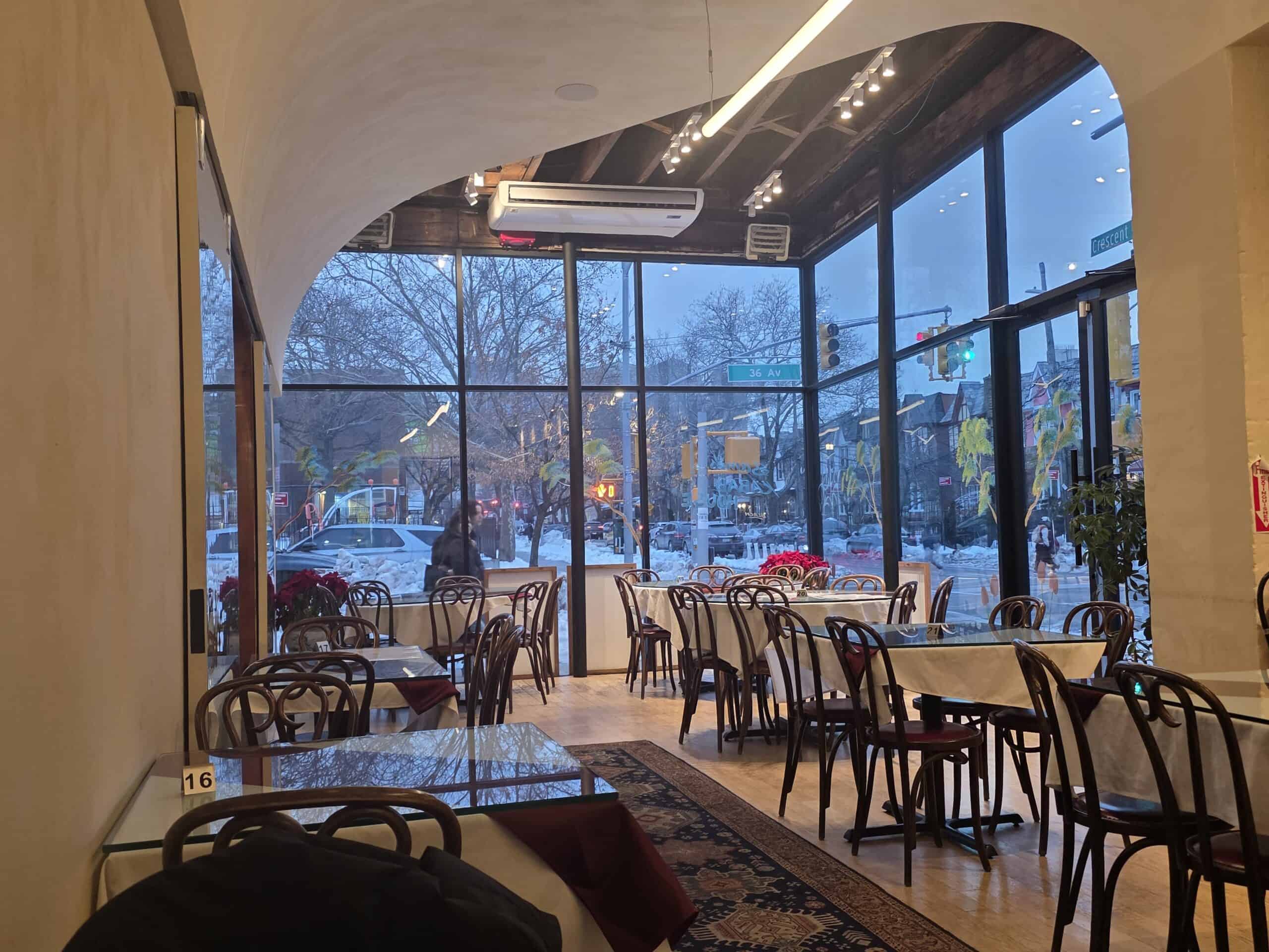 Bright casual dining room interior at Sami's Kabab House with large floor-to-ceiling corner windows and wooden chairs