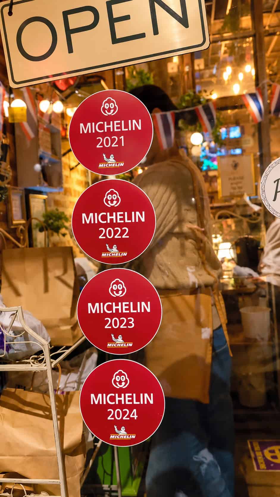 Red Michelin Bib Gourmand stickers from 2021 through 2024 displayed on the glass window at SaRanRom Thai