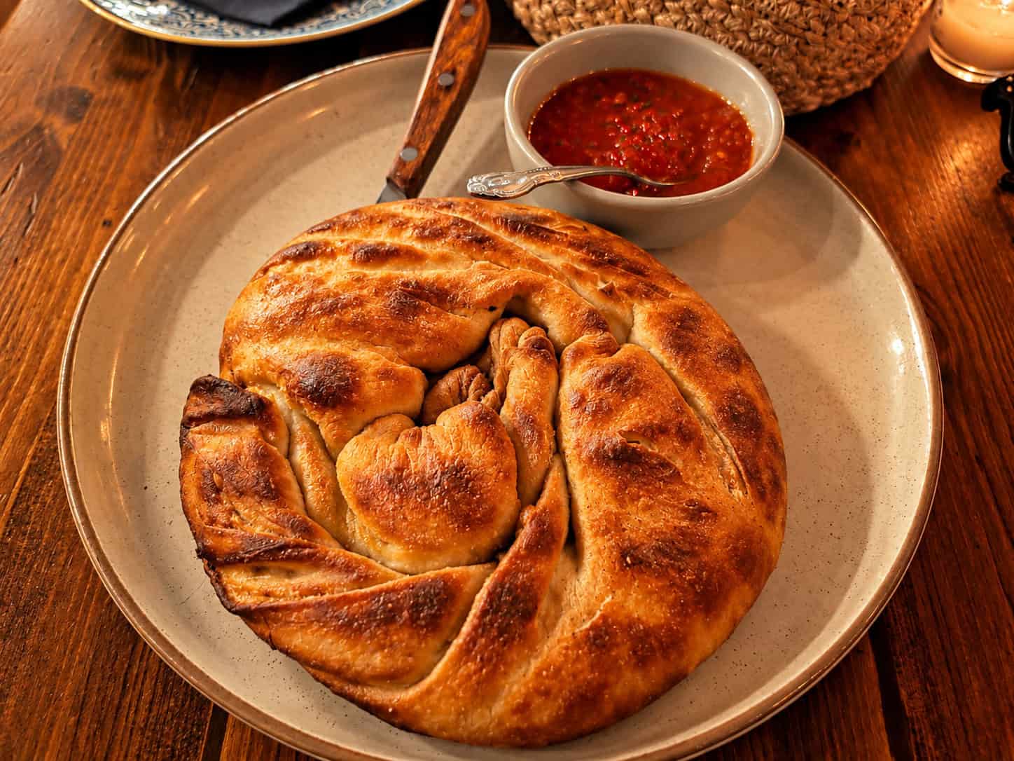 Spiral-shaped golden Skopelitiki cheese pie served on a ceramic plate with roasted red pepper jam