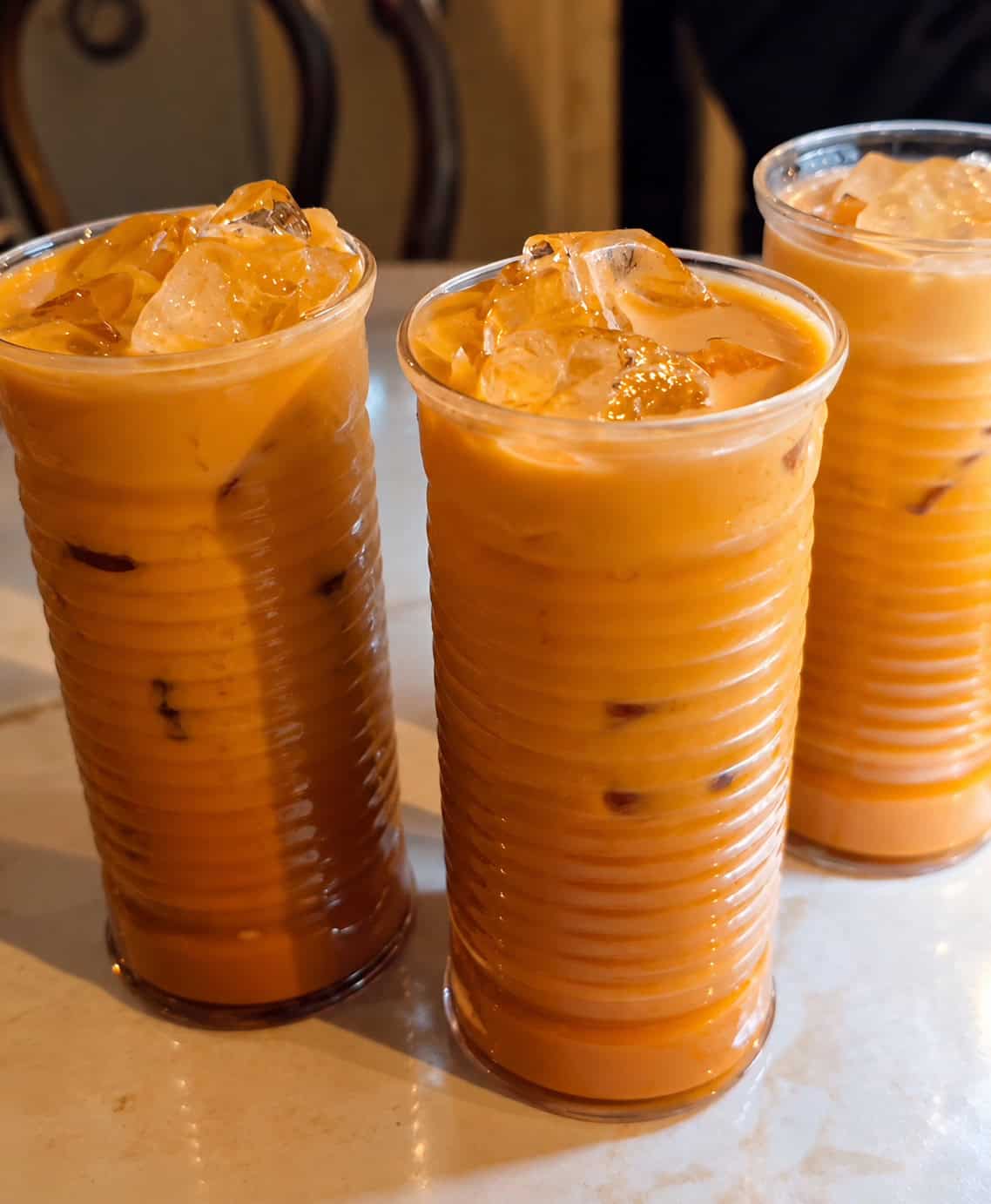 Three tall glasses of sweet creamy Thai iced tea filled with crushed ice at SaRanRom Thai