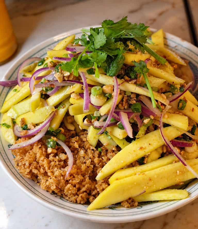 Yum Pla Duk Fu with crispy fluffy catfish topped with green mango salad red onions and cilantro